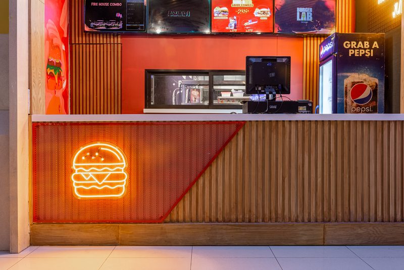 Neon signage set into the fluted counter front at Burger Lab, Lucky One Mall.